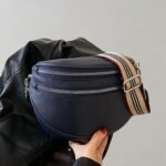 Stilig navy blå fanny pack med trendy stripet reim og skinnjakke.