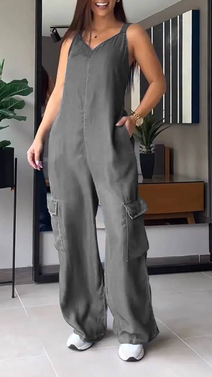 Avslappet grå jumpsuit i moderne innendørs setting med trendy innredning og grønt.