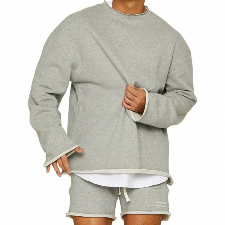 Avslappet og trendy antrekk med grå sweatshirt, hvit skjorte og korte shorts.