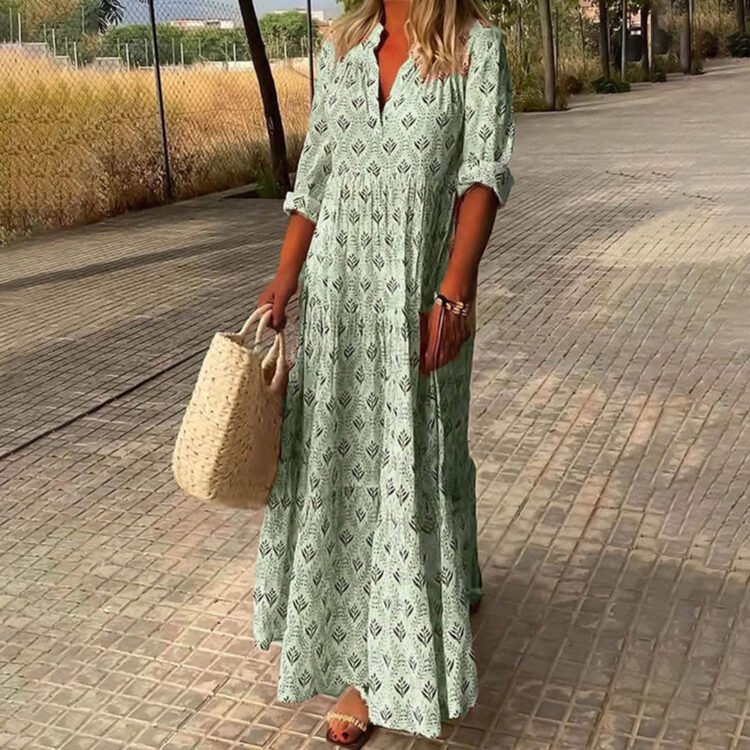 Person i grønn sommerkjole med strandveske og sandaler på solrik promenade.