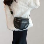 Luksuriøs hvit faux fur kåpe med svart crossbody-veske og elegante bukser.