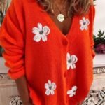 Oransje cardigan med blomsterapplikasjoner, halskjede og shorts for avslappet stil.