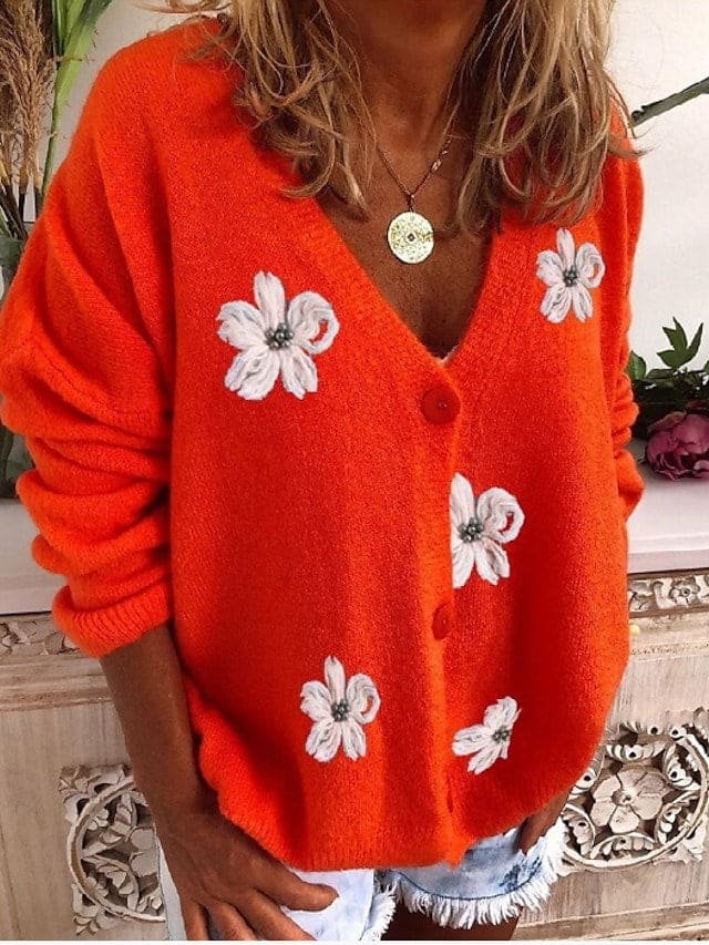 Oransje cardigan med blomsterapplikasjoner, halskjede og shorts for avslappet stil.