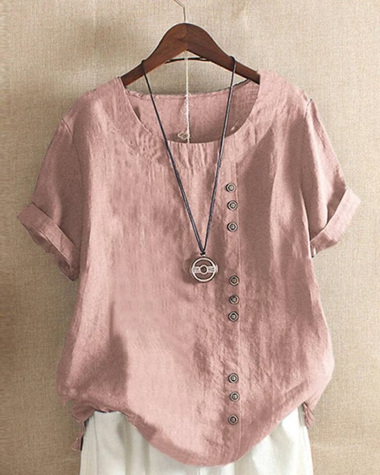 Stilig rosa bluse med asymmetrisk knappdesign og smykkependant.