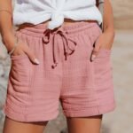 Sommerlig rosa shorts og hvit bluse outfit for avslappet sommerstil utendørs.