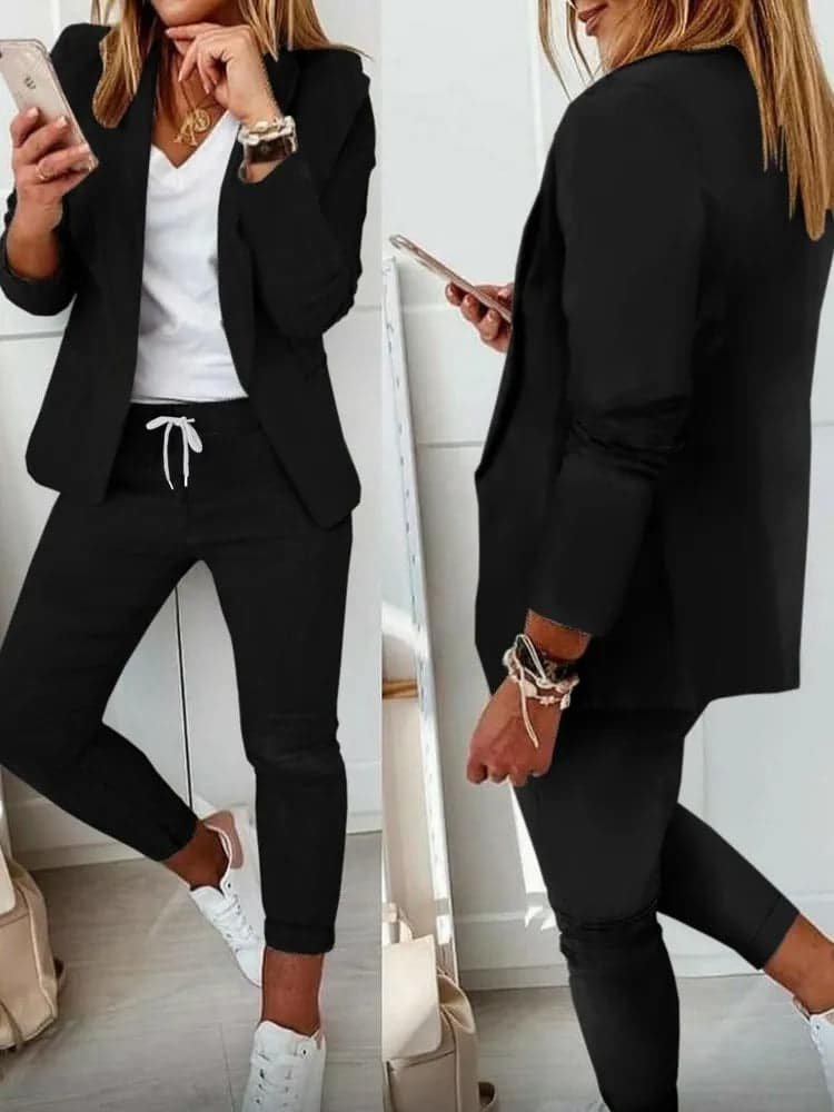 Stilig outfit med svart blazer, hvit t-skjorte, sorte joggerbukser og hvite sneakers.