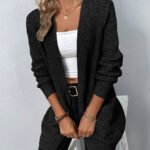 Stilig svart cardigan og hvit crop top med elegante detaljer.