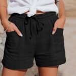 Sommerlig antrekk: Svarte shorts og hvit knyttet topp med trendy detaljer.