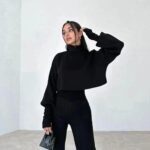 Moderne chic stil: Svart turtleneck, bukser og håndveske i lyst rom.